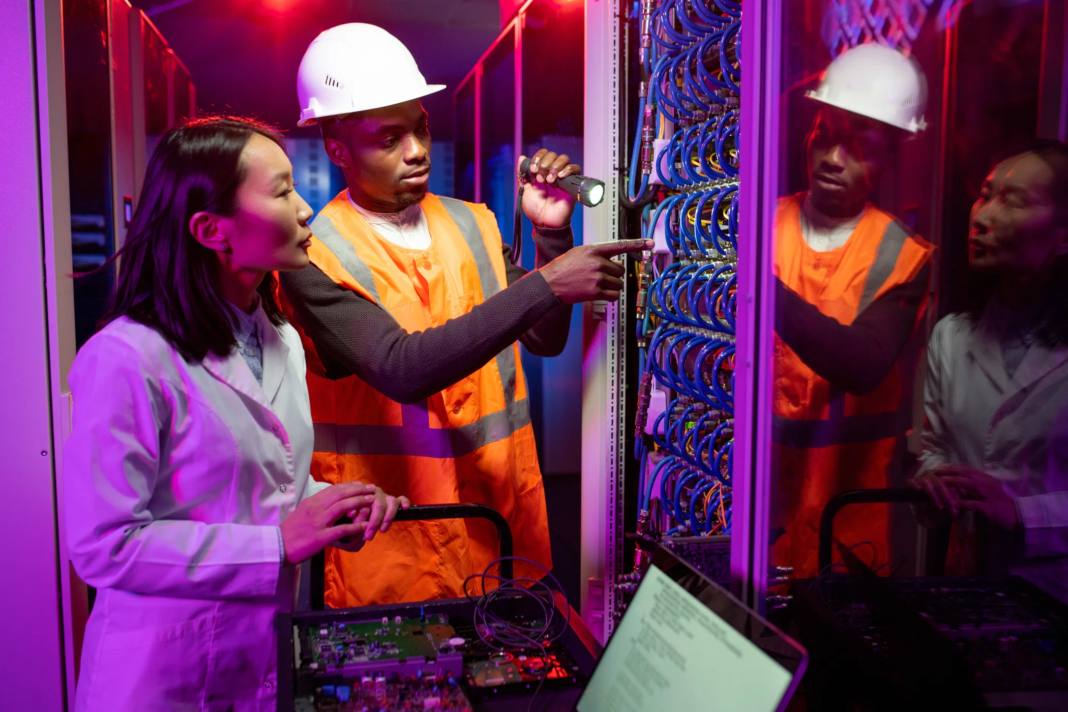 Technicians inspecting network equipment in a data centre